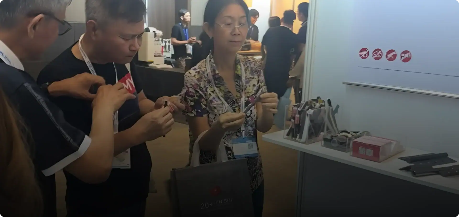 Group of people examining a new tech gadget at a trade show booth, showcasing innovative products and engaging with the latest technology solutions.