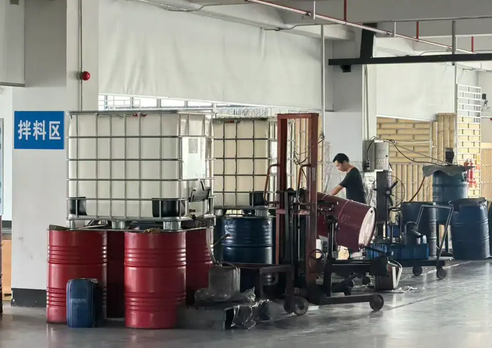 Industrial liquid storage tanks and barrels in a warehouse setting for chemical or liquid storage.