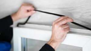 Close-up of hands installing weatherstripping on a door frame for improved sealing and energy efficiency.